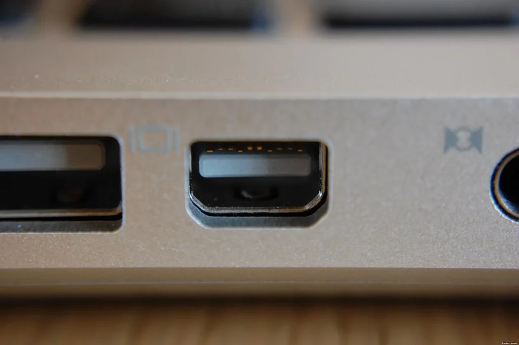 Mini DisplayPort female receptacle on a slim notebook chassis showing friction-fit chamfered corners and monitor icon